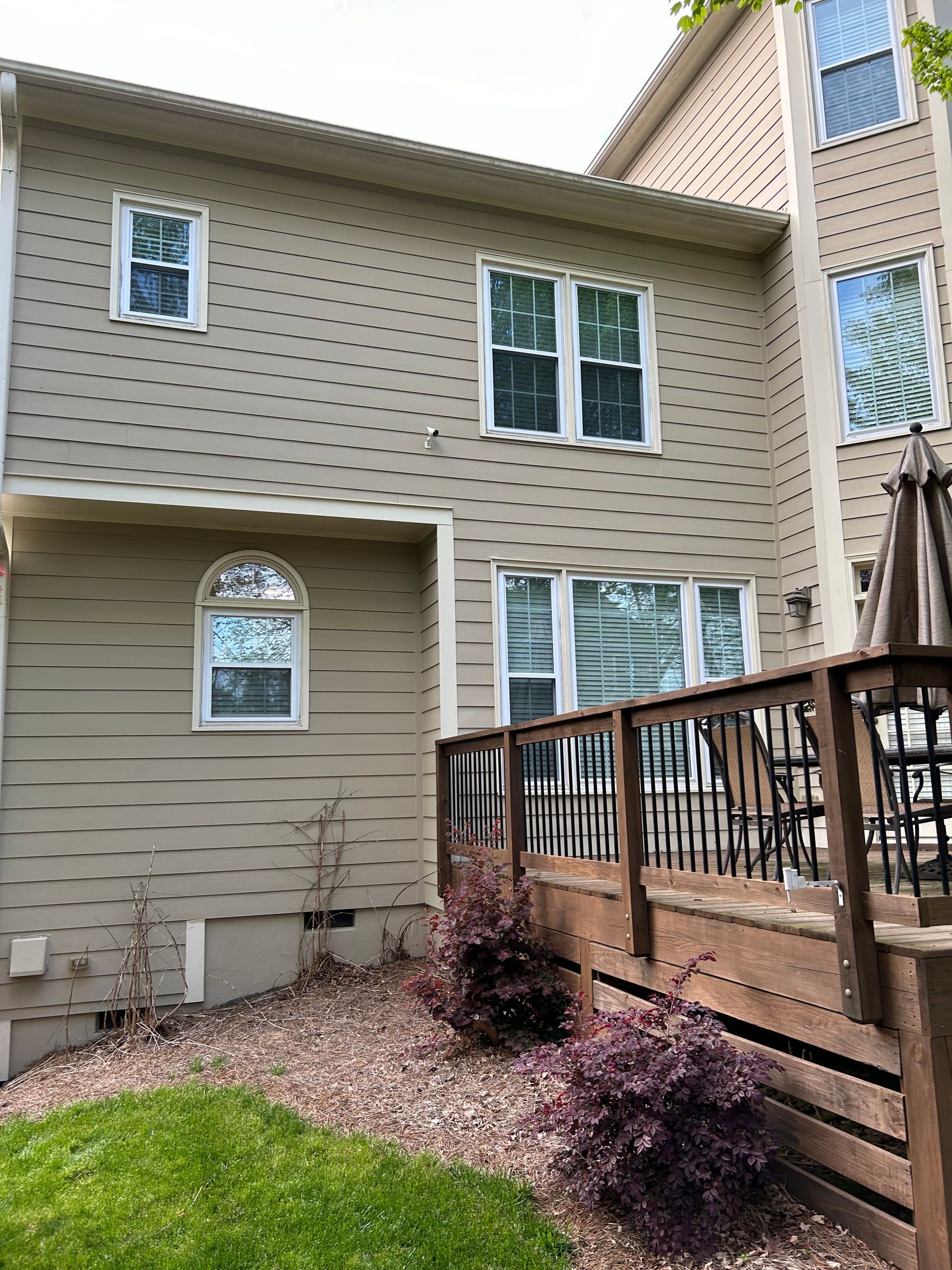 The back of a house with a deck and a lot of windows
