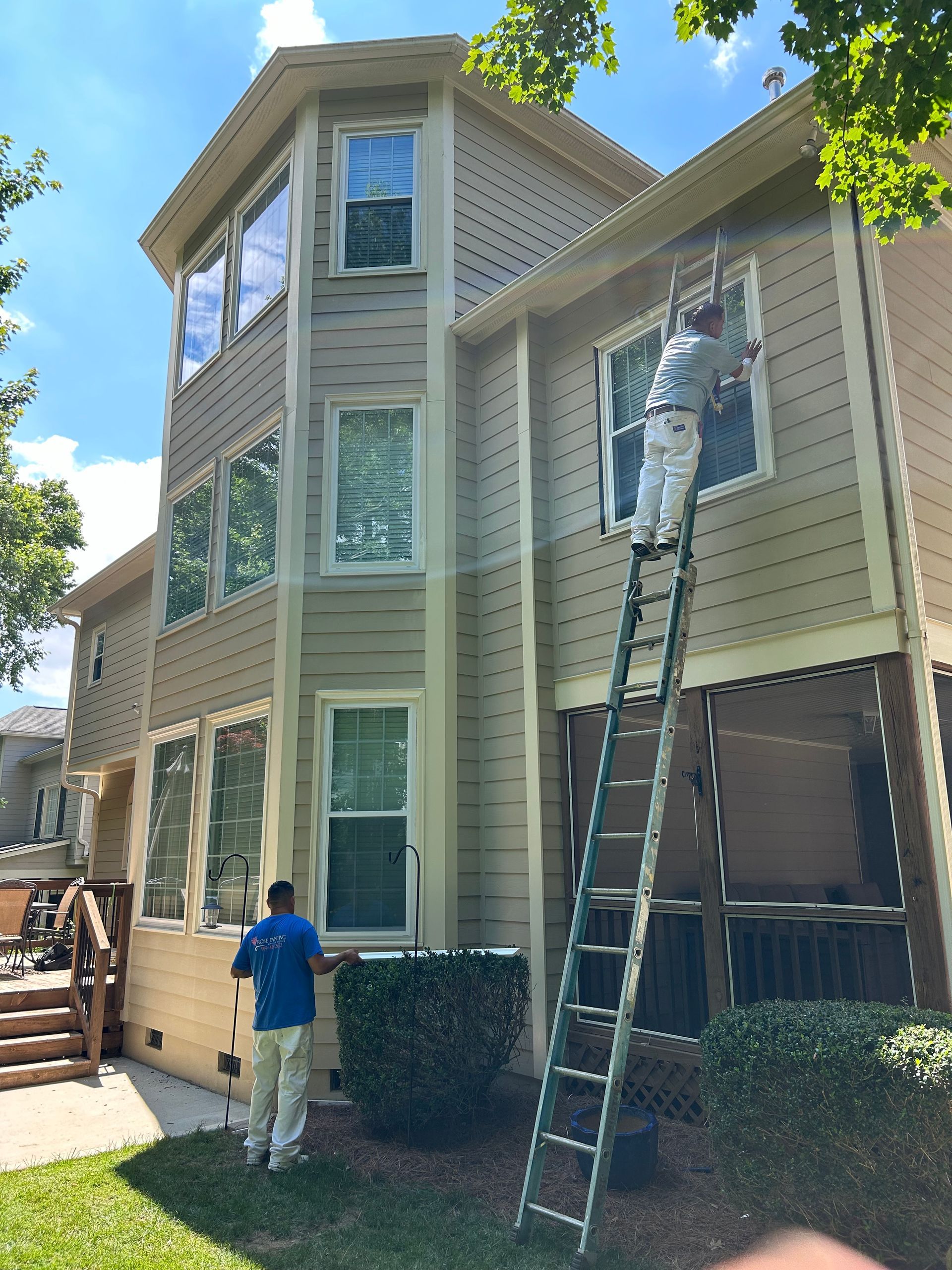 A man is painting a house with a ladder.