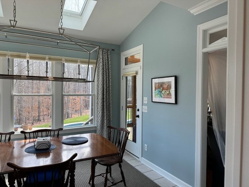 A dining room with a table and chairs and a skylight