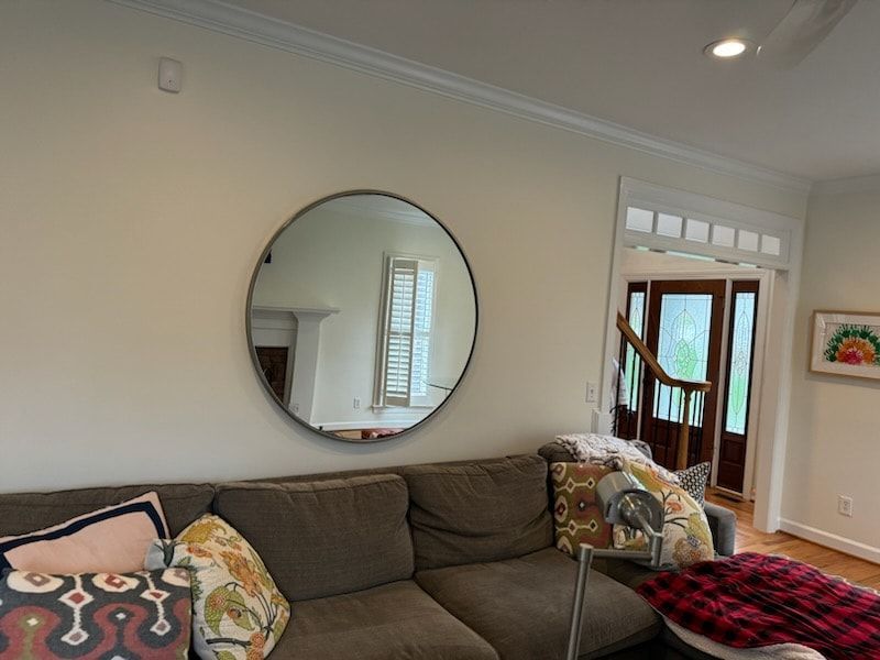 A living room with a couch and a round mirror on the wall