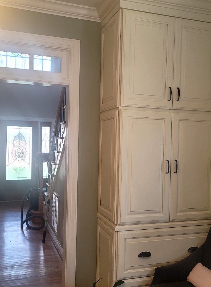 A room with white cabinets and a staircase in the background