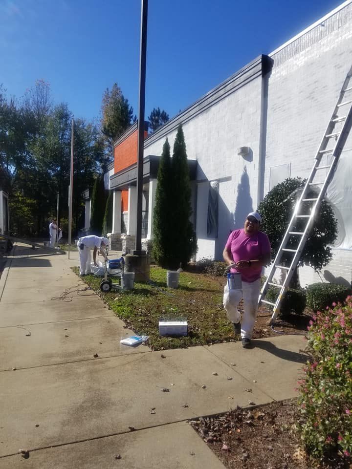 A man in a pink shirt is standing in front of a building with a ladder