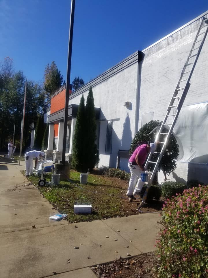 A man on a ladder paints the side of a building