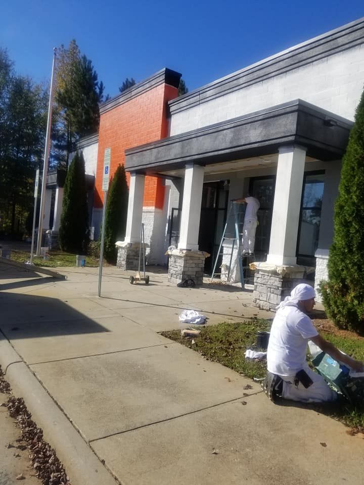 A man is kneeling in front of a building that is being painted