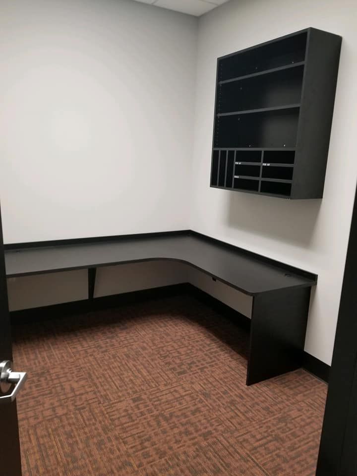 An empty room with a desk and shelves on the wall