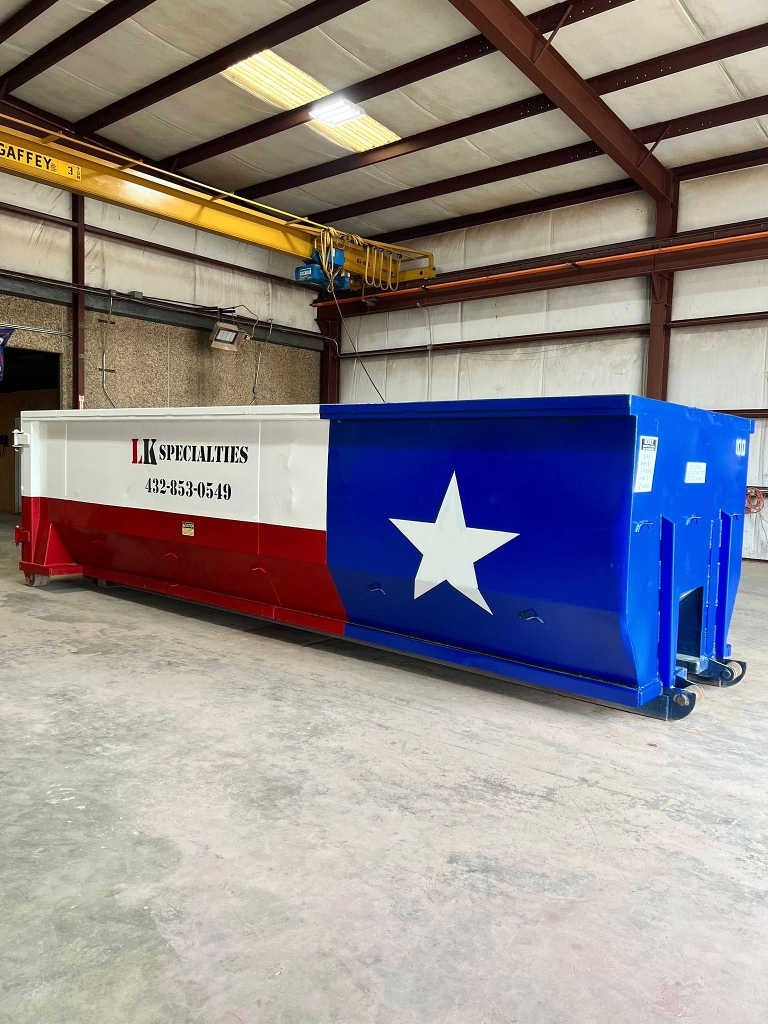 A dumpster painted with the Texas state flag in a warehouse.