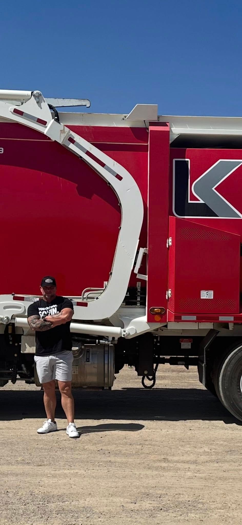 Man standing next to a large red and white truck with the logo 