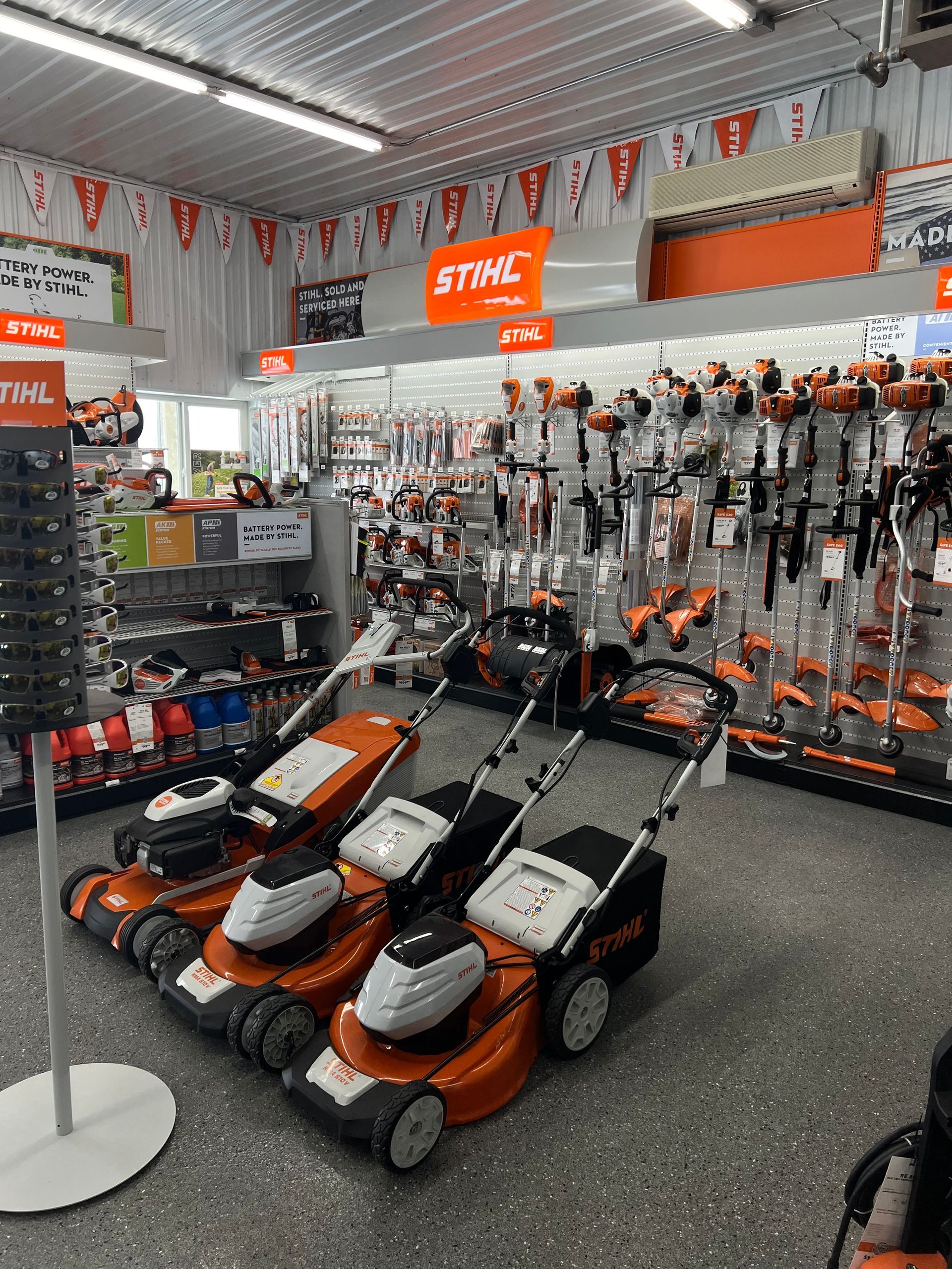 A row of lawn mowers are lined up in a store.