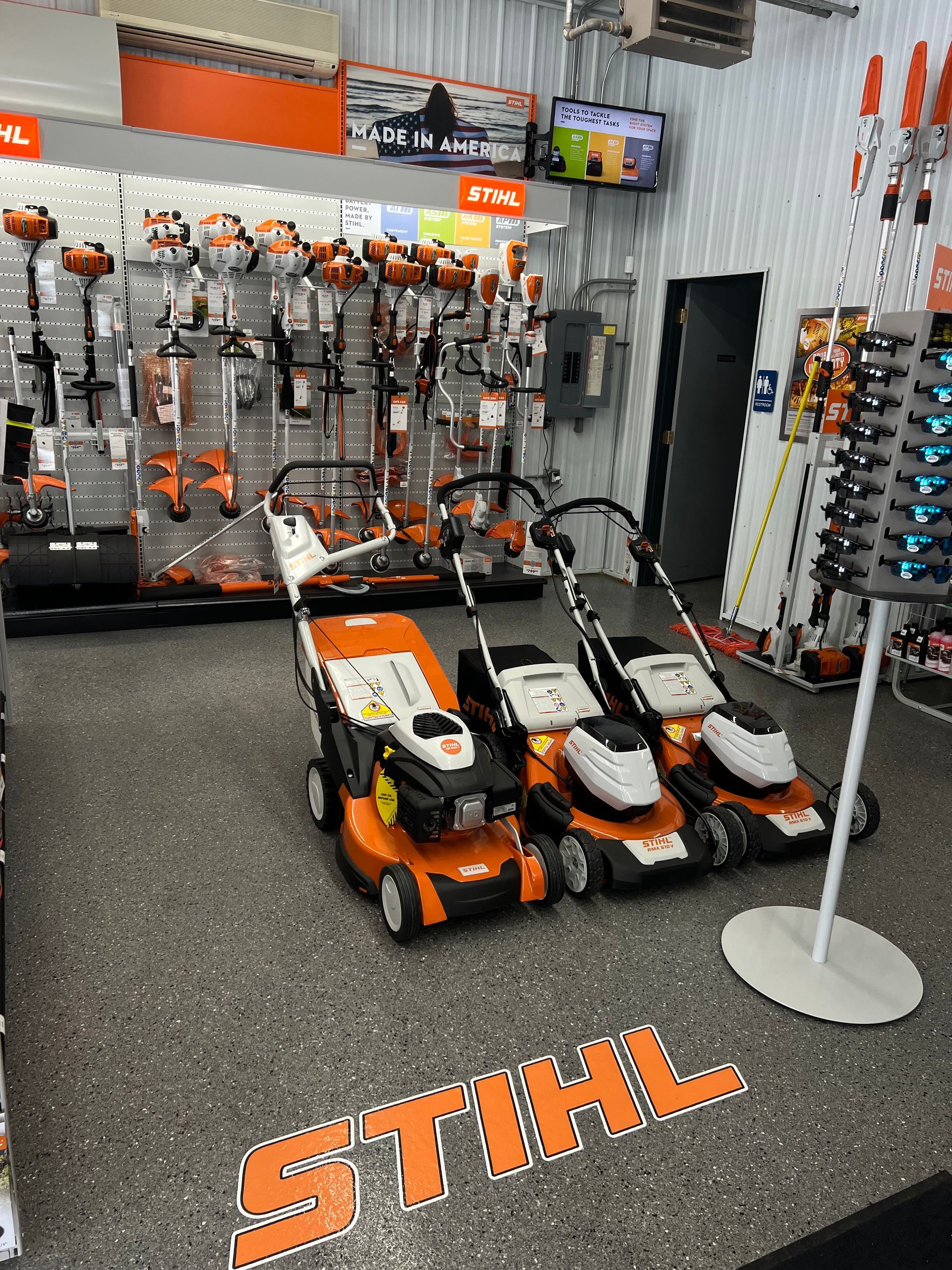A stihl lawn mower is sitting on the floor of a store.