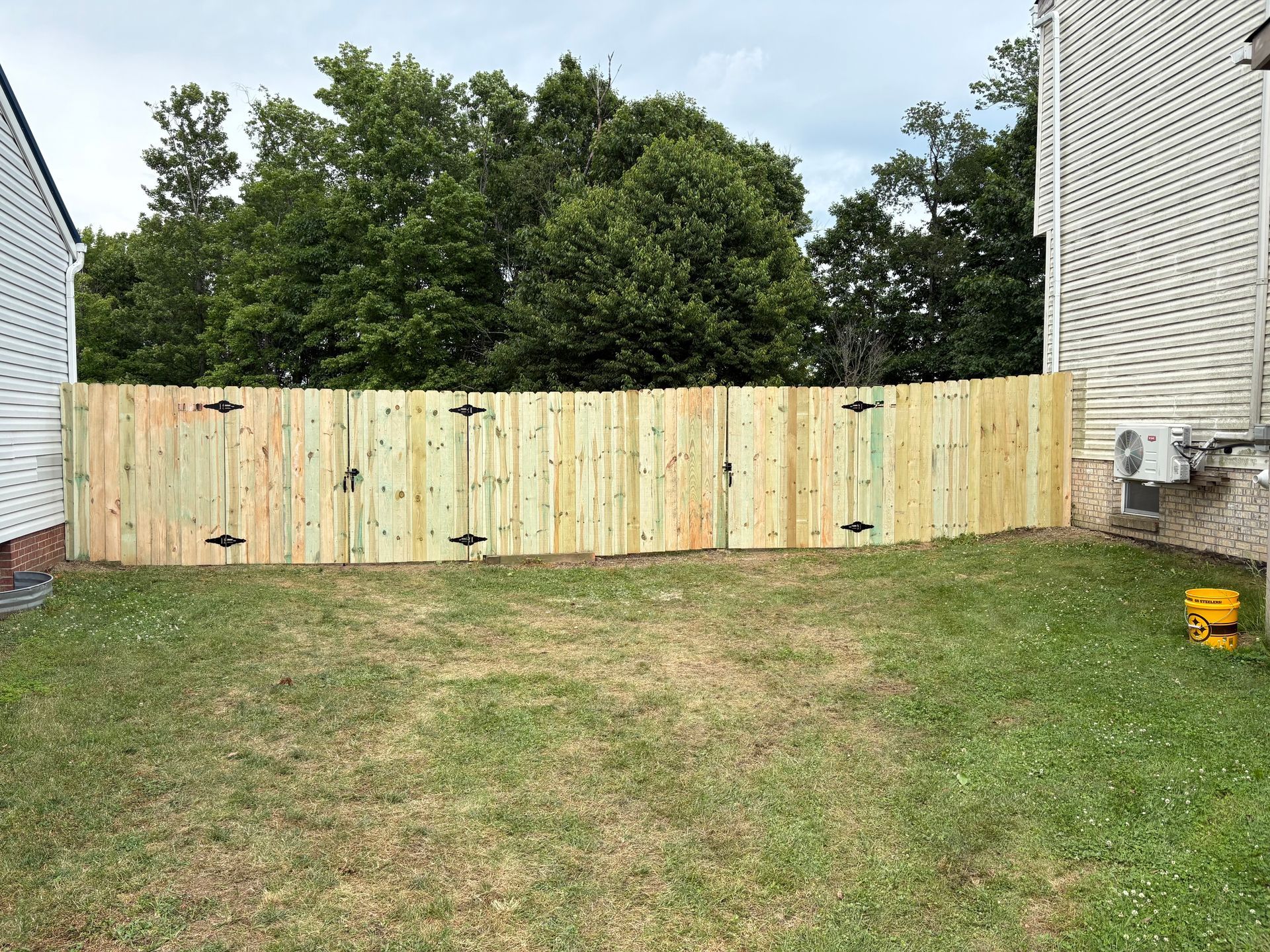 Backyard with a newly built wooden fence between two houses and grass in the foreground