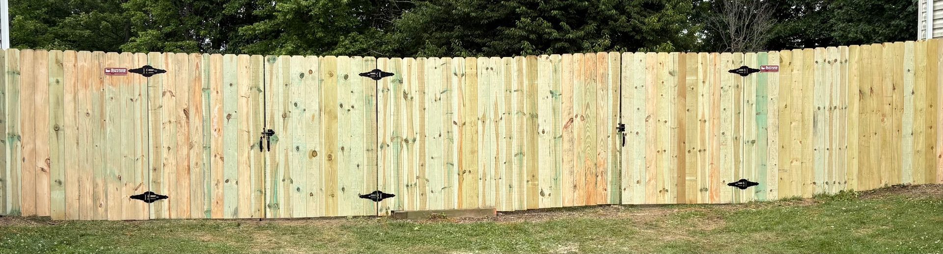 Weathered wooden fence with black clip-on lights in a grassy backyard