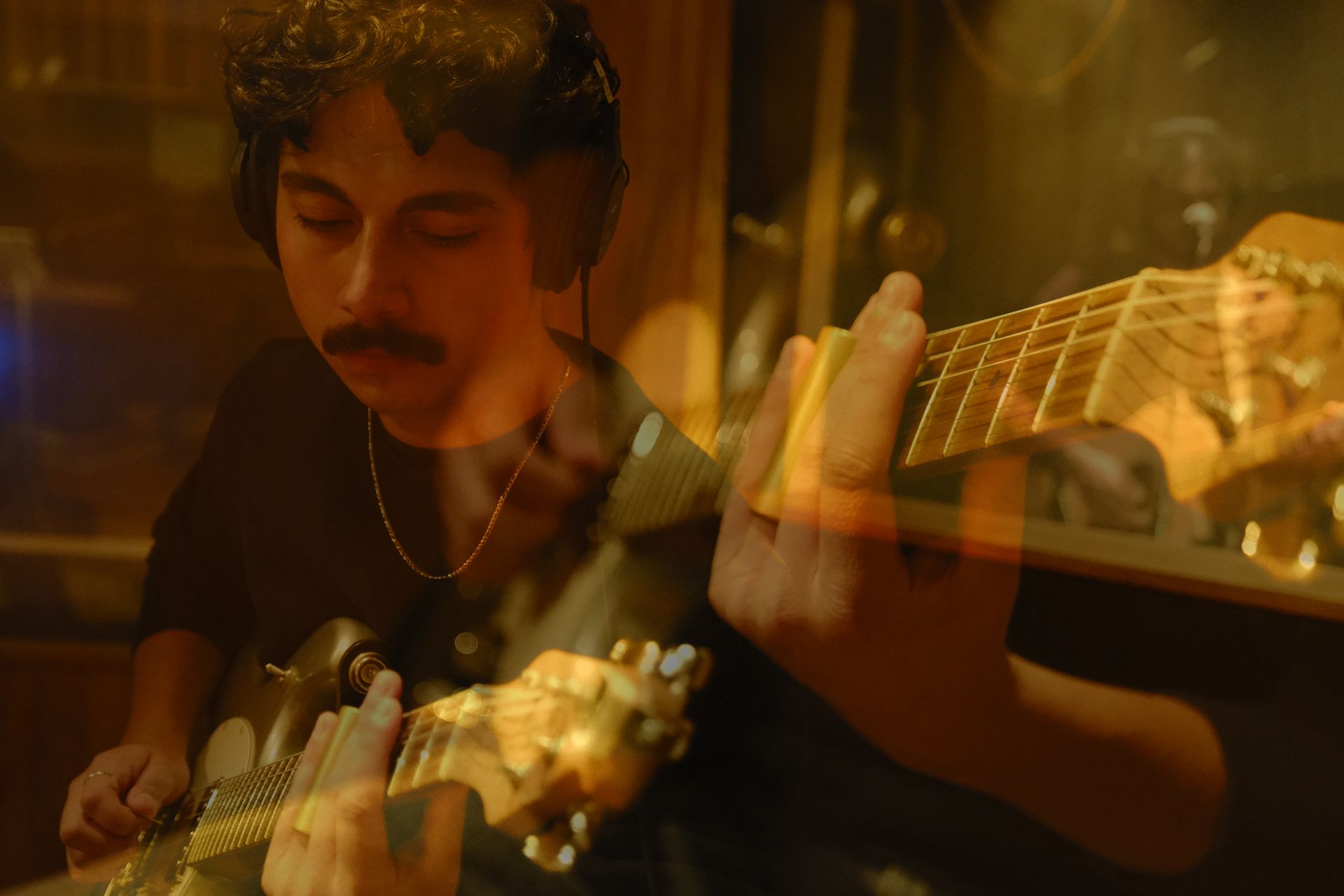 A man with a beard is singing into a microphone while playing a guitar.