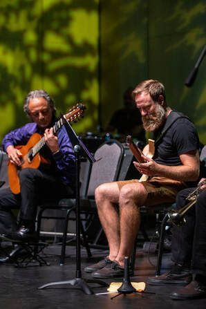 Two men are playing guitars on a stage.