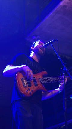 A man is playing a guitar and singing into a microphone on a stage.