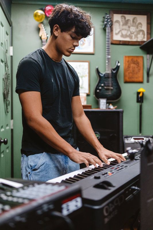 A young man is playing a keyboard in a room.