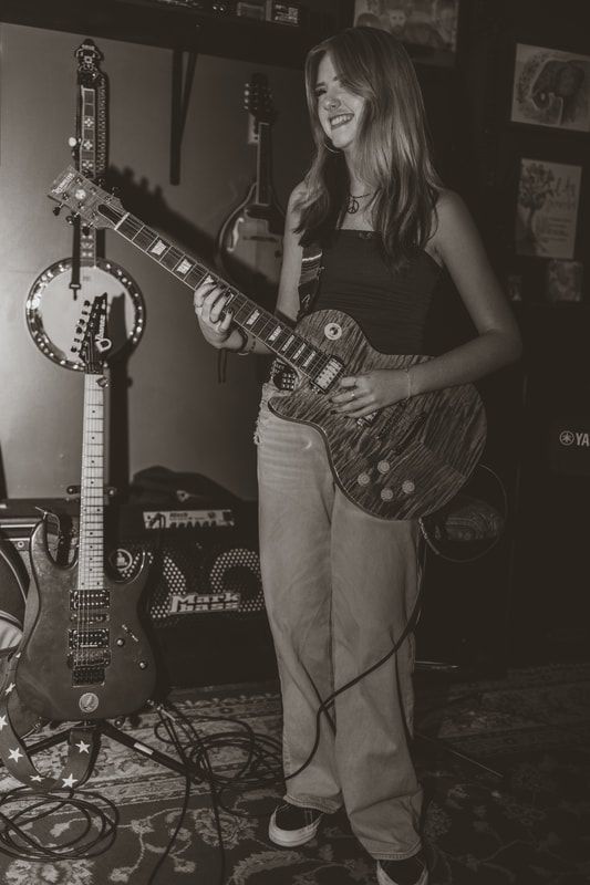 A woman is holding a guitar in a black and white photo.