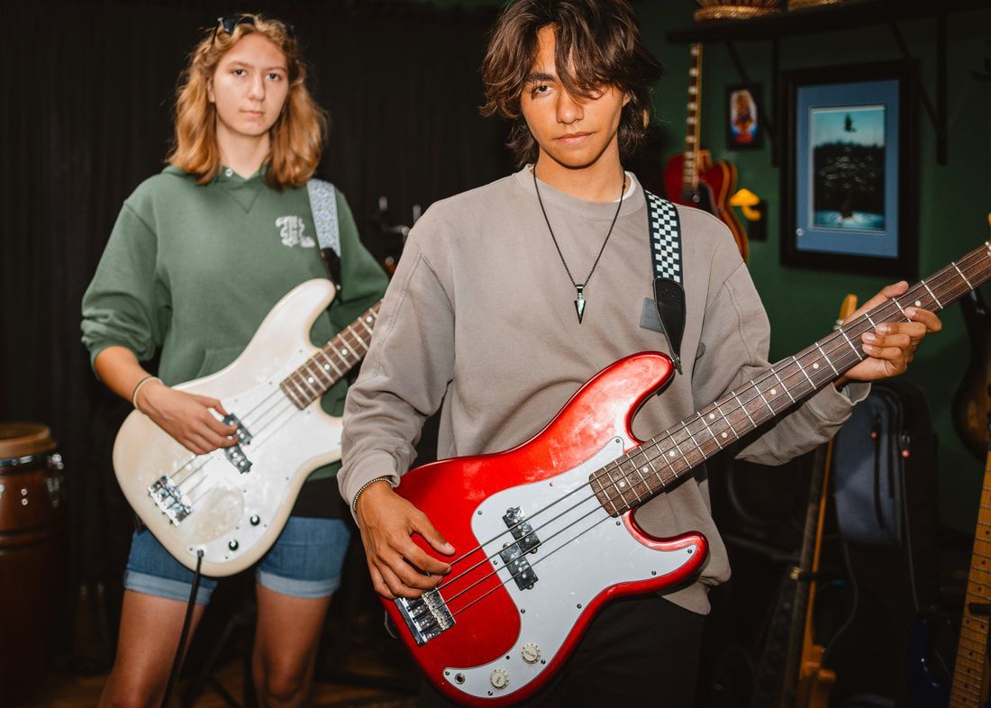 A man and a woman are standing next to each other holding guitars.