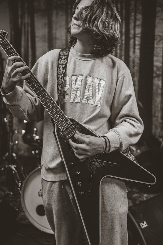A young man is playing a guitar in a black and white photo.