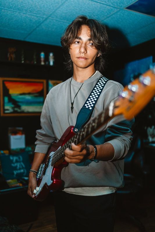 A young man is playing a red electric guitar in a room.
