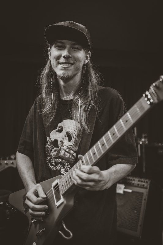A man with long hair is playing a guitar in a black and white photo.