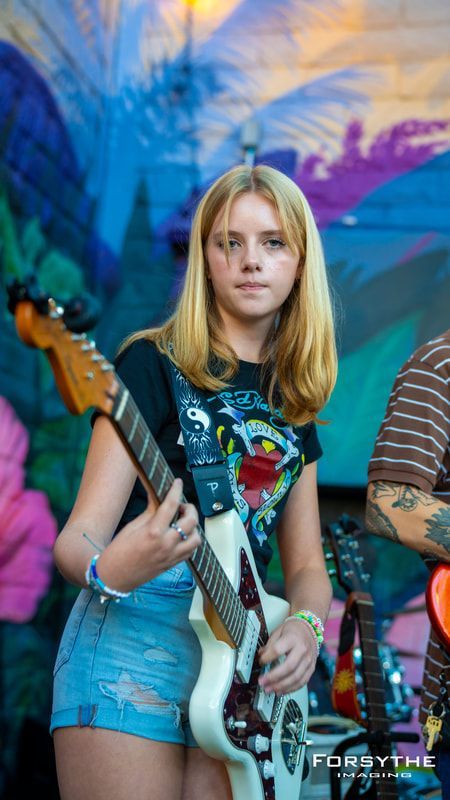A young girl is playing a guitar on stage.