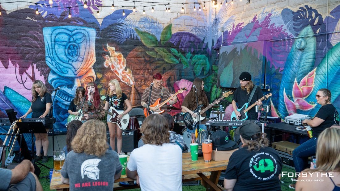 A group of people are sitting at a table watching a band perform on stage.