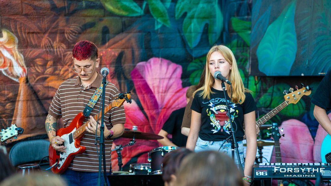 A man is playing a guitar and a woman is singing into a microphone.