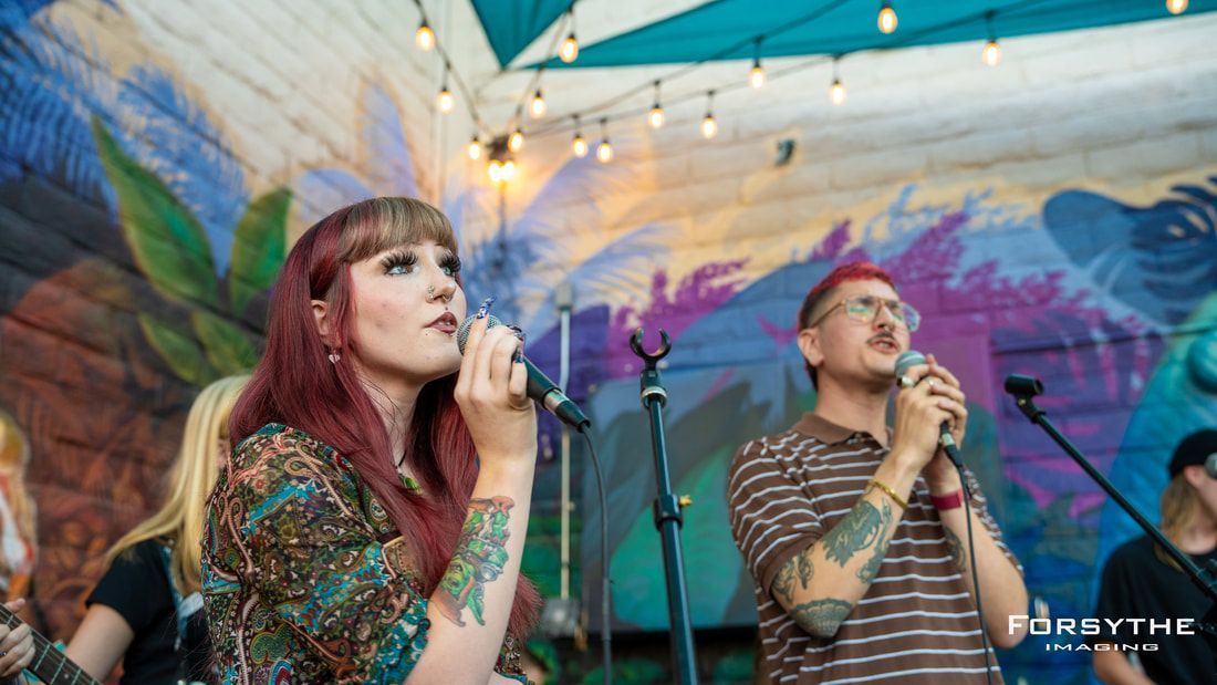 A man and a woman are singing into microphones on a stage.