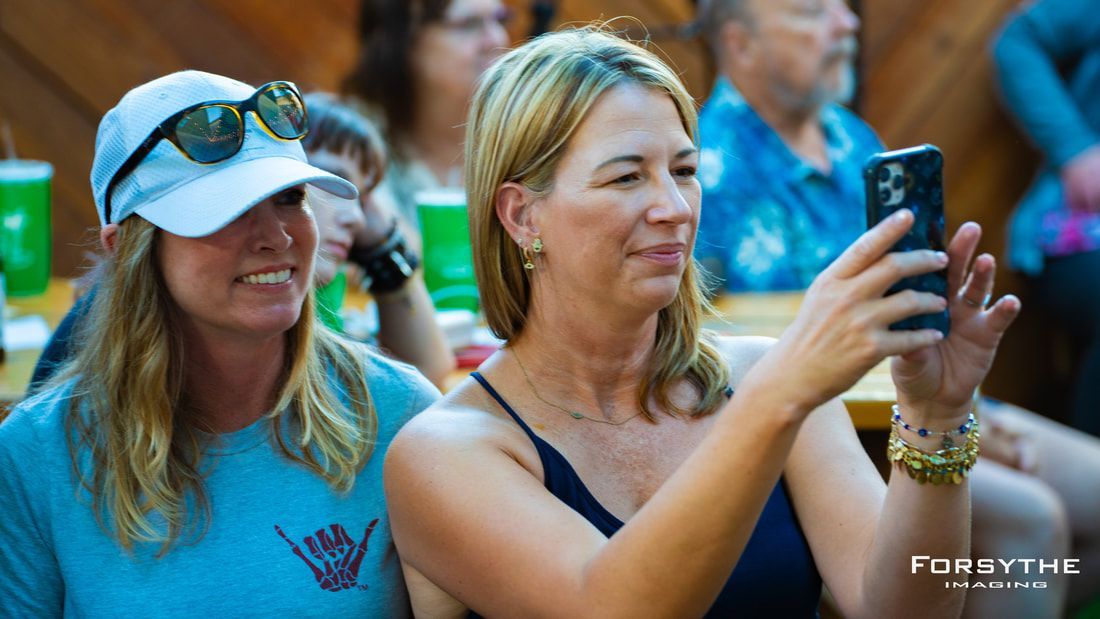 Two women are taking a picture of themselves with their cell phones.
