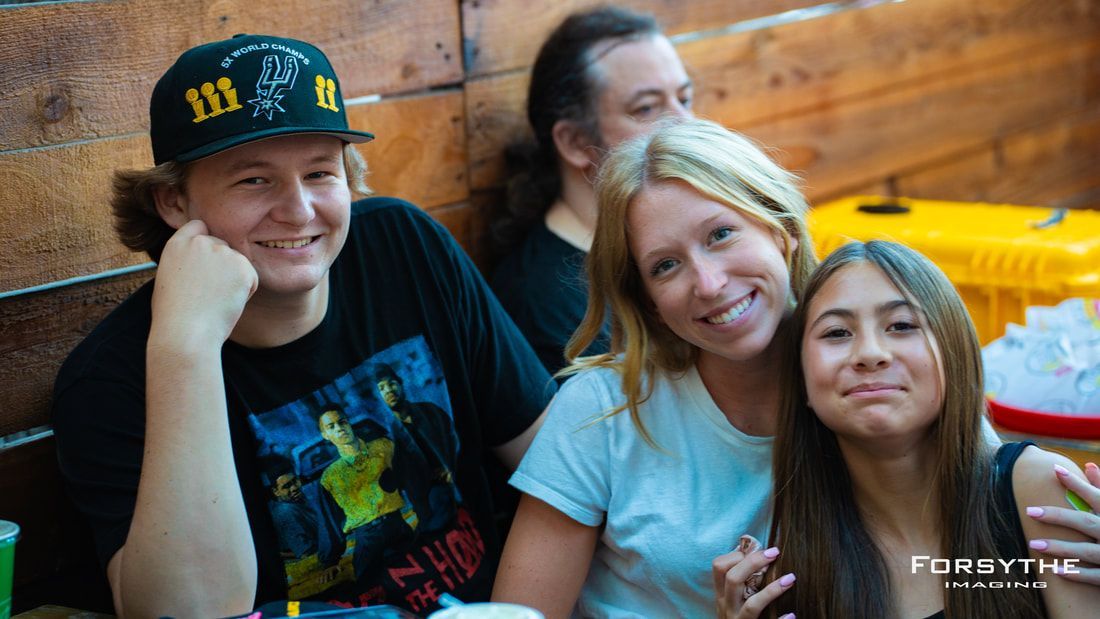 A group of people are posing for a picture while sitting at a table.