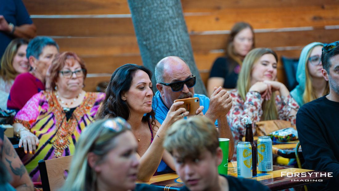 A group of people are sitting at tables eating food and drinking beer.