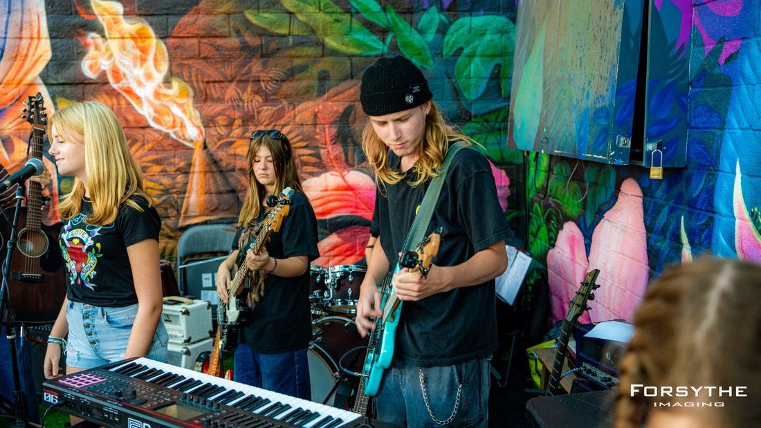 A group of young people are playing instruments on a stage.