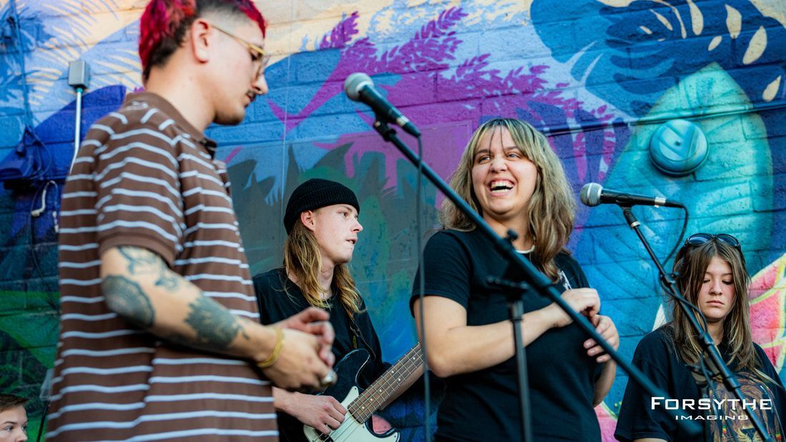 A group of people are standing in front of a microphone.