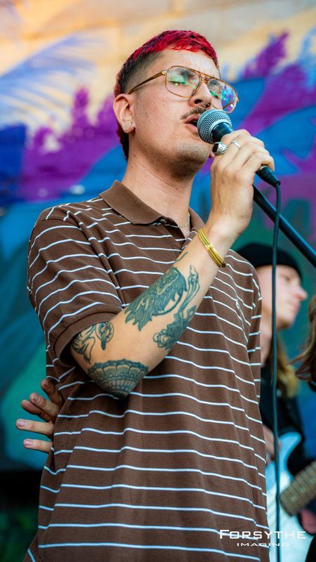 A man in a striped shirt is singing into a microphone.