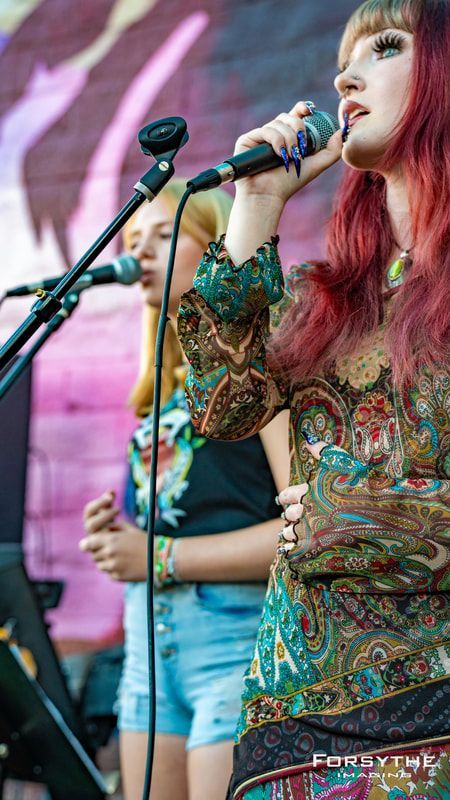 Two women are singing into microphones on a stage.