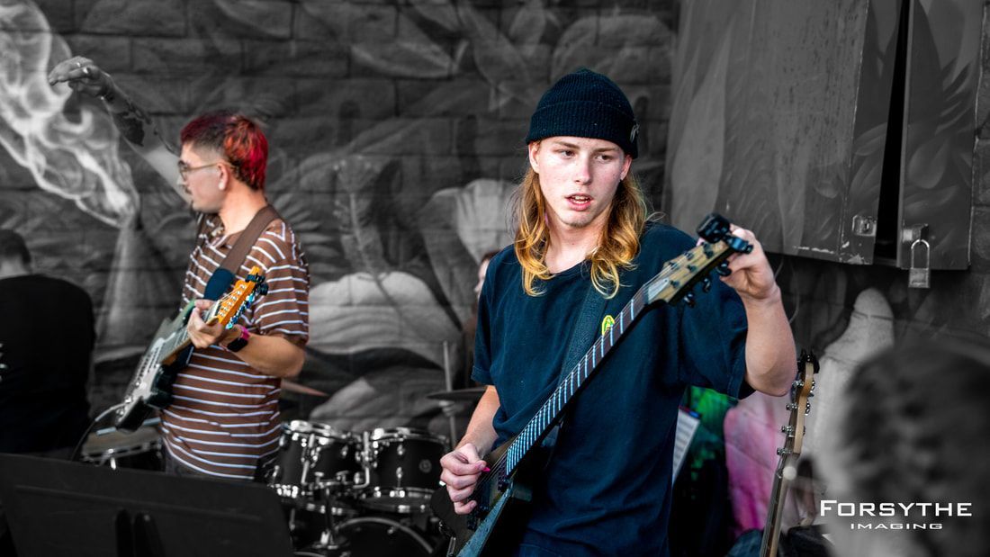 A man is playing a guitar on stage in front of a crowd.