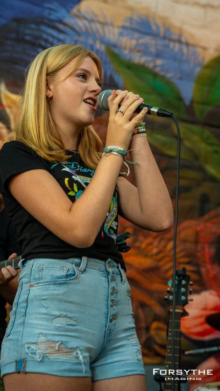 A young woman is singing into a microphone on a stage.