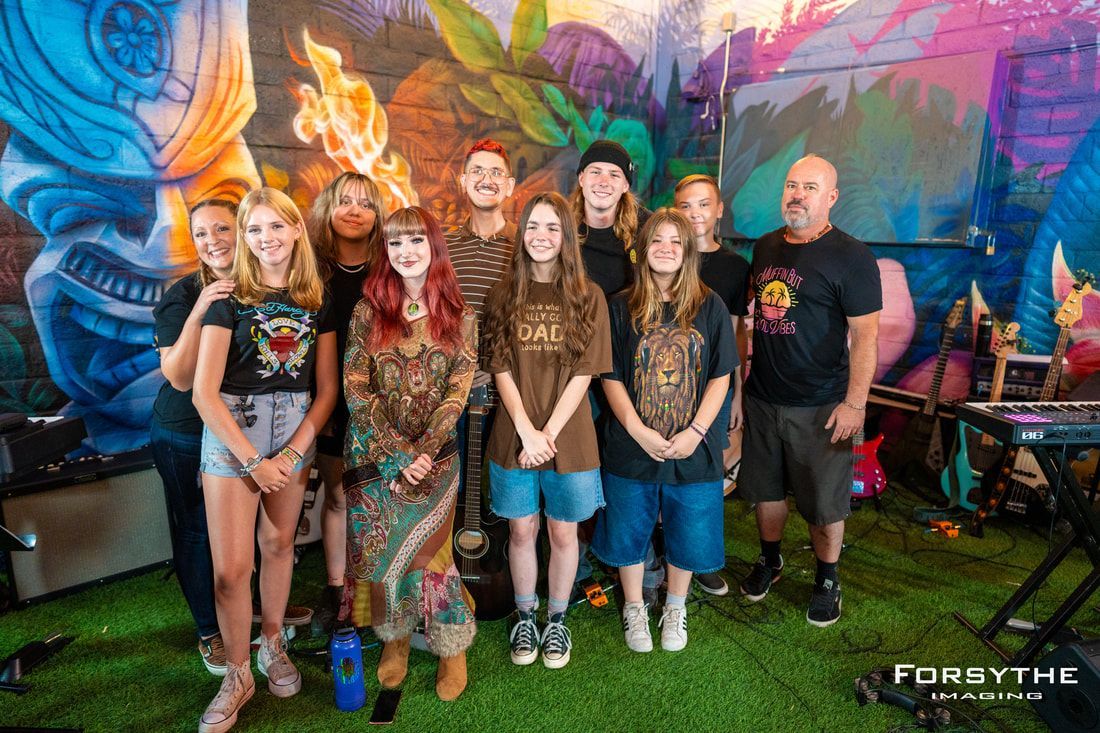 A group of people are posing for a picture in front of a mural.