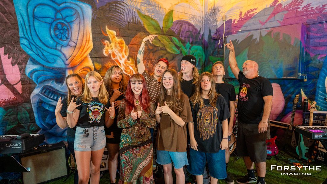 A group of people are posing for a picture in front of a mural.