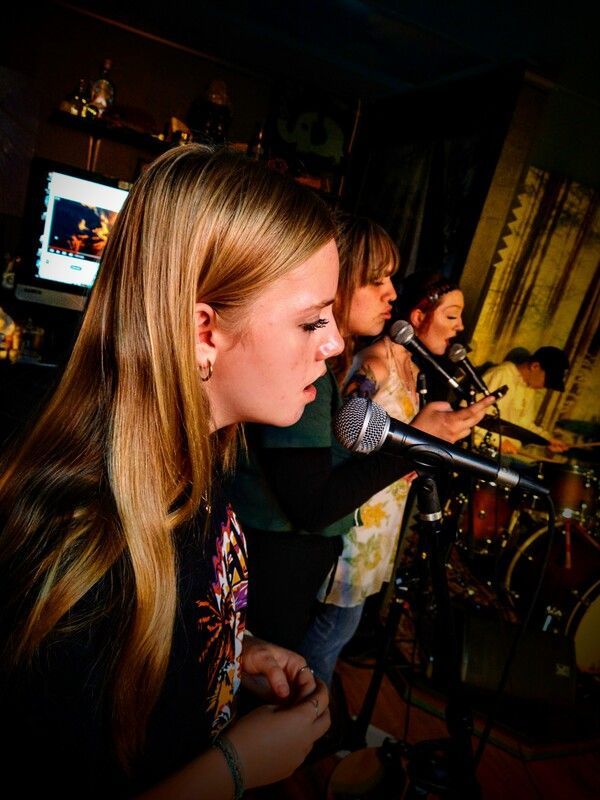A group of women are singing into microphones on a stage.