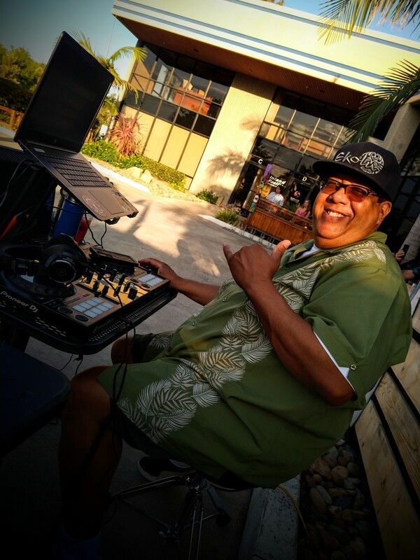 A man in a green shirt is sitting at a table with a laptop on it.