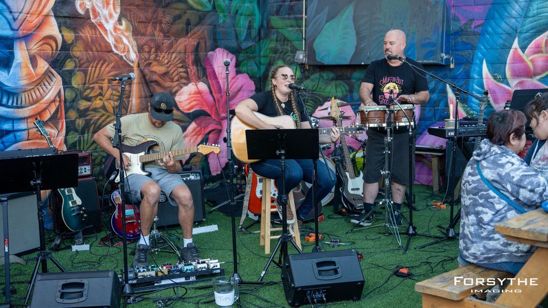 A group of people are playing instruments on a stage in front of a mural.