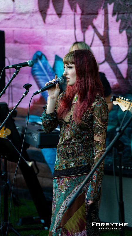 A woman is singing into a microphone on a stage.