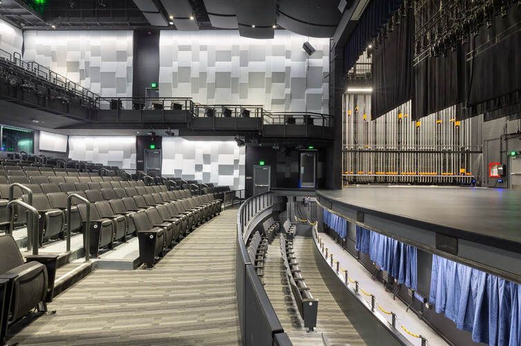A large empty auditorium with rows of seats and a stage.