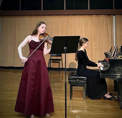A woman is playing a violin and another woman is playing a piano.
