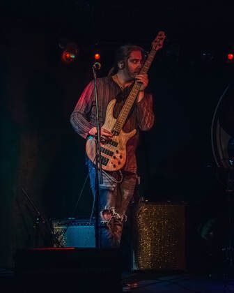 A young woman in a black dress is holding a violin.