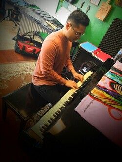 A man is sitting on a bench playing a keyboard.