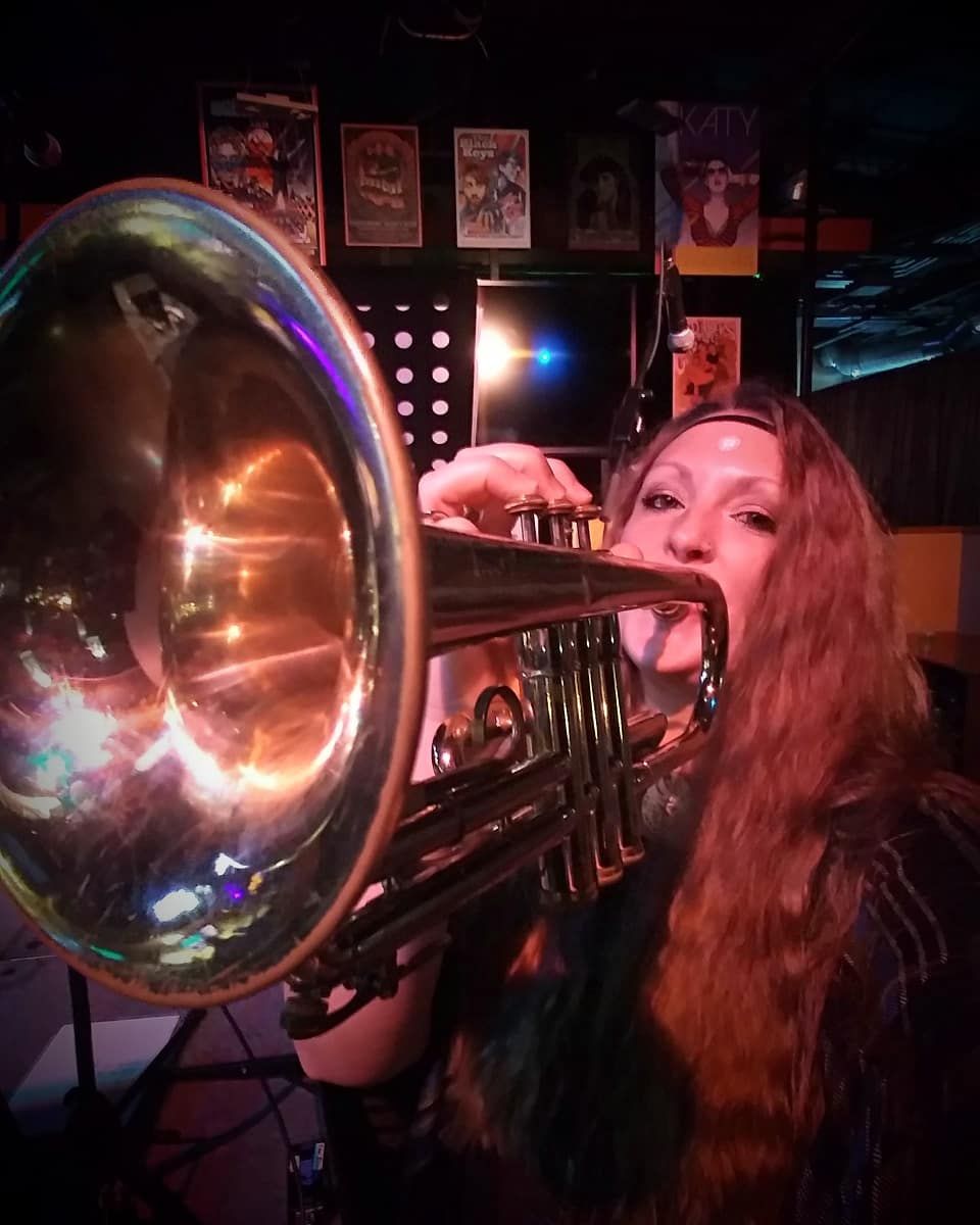 A woman is playing a trumpet in a dark room