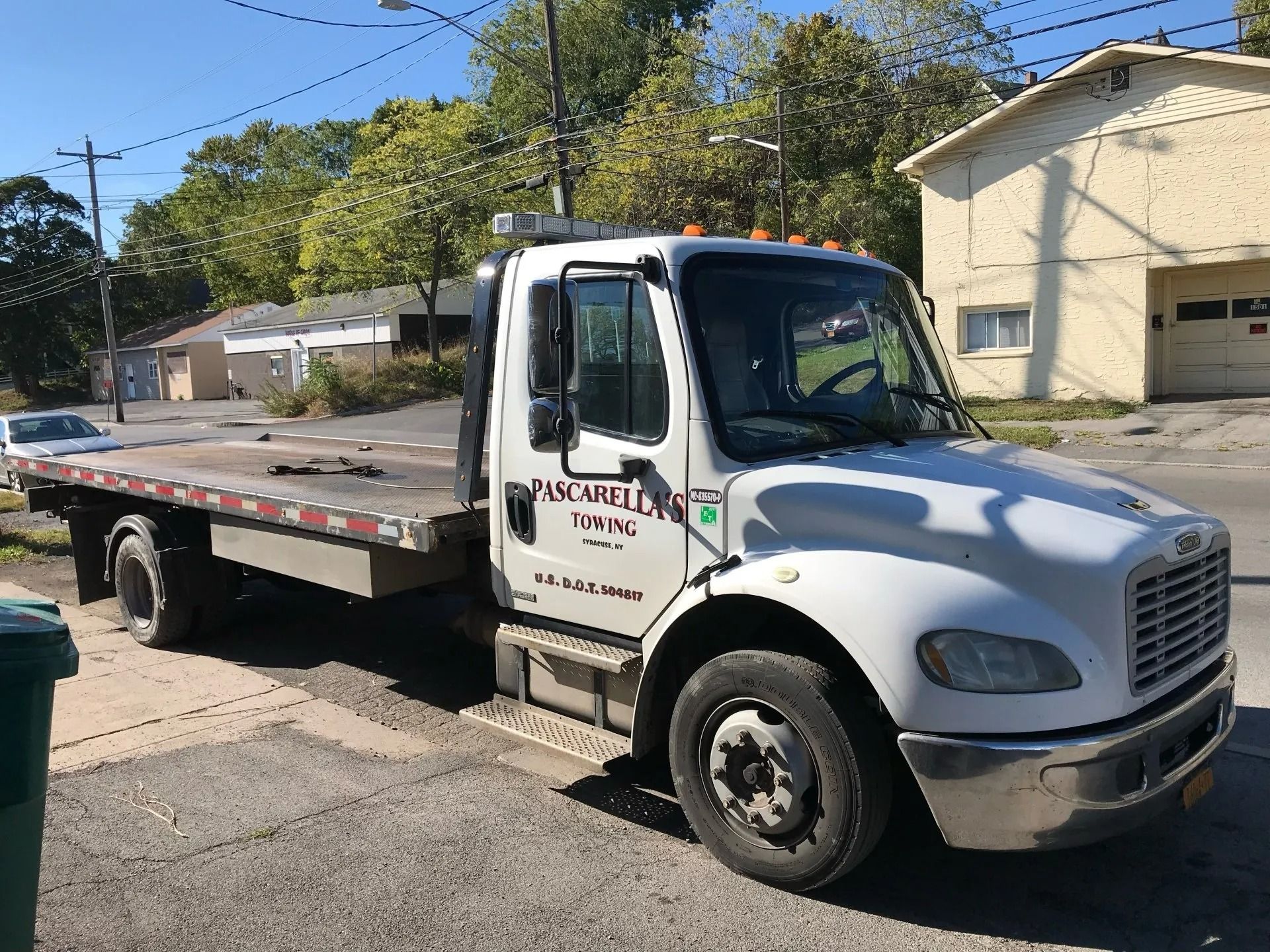 White tow truck parked on a street in front of buildings.