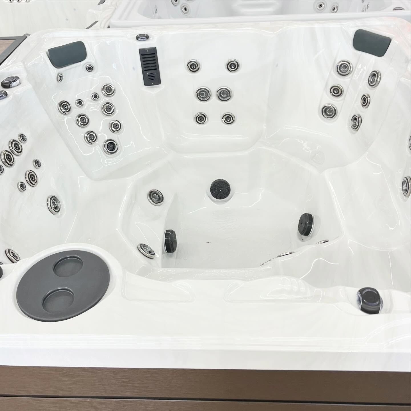 White hot tub with multiple jets and dark headrests, viewed from above.